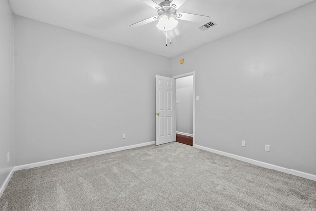 carpeted spare room featuring baseboards, visible vents, and ceiling fan