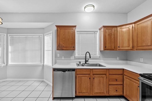 kitchen with light tile patterned floors, stainless steel appliances, light countertops, and a sink