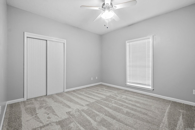 unfurnished bedroom with a ceiling fan, carpet flooring, baseboards, and a closet