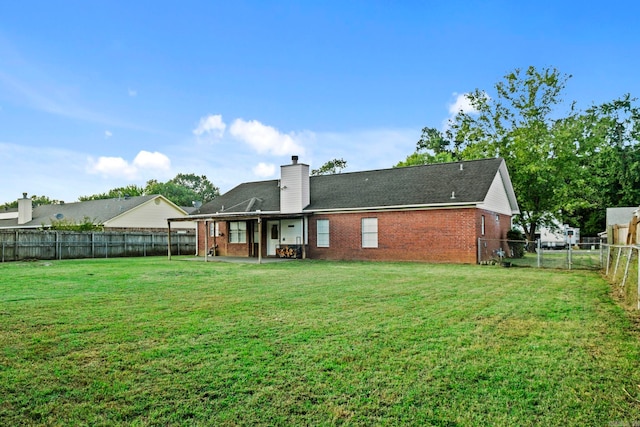 back of house featuring brick siding, a lawn, a chimney, and a fenced backyard