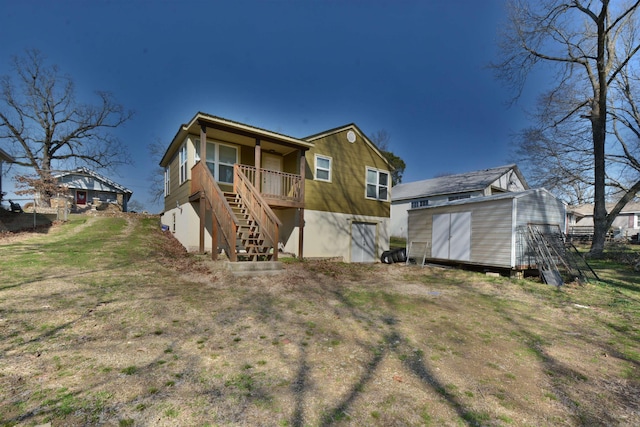 back of house featuring stairs, an outdoor structure, and a shed