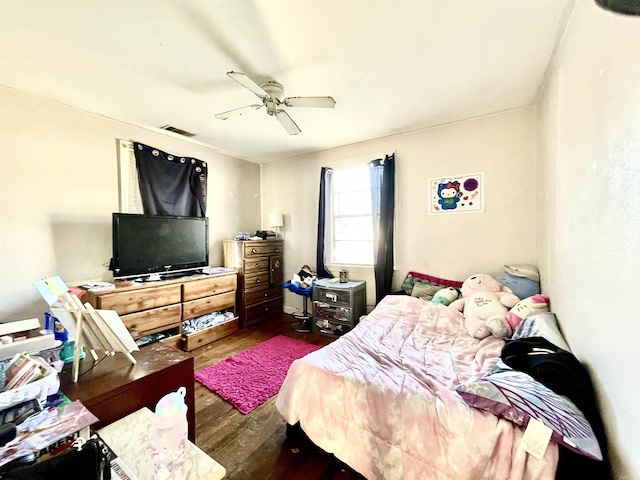 bedroom with ceiling fan, visible vents, and wood finished floors