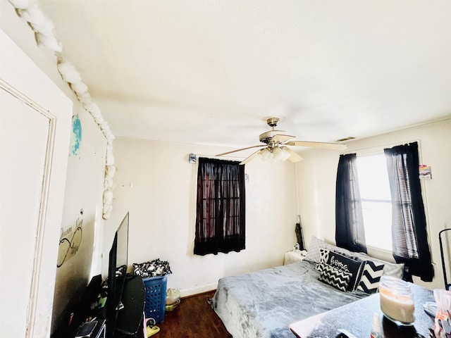 bedroom featuring ceiling fan, visible vents, baseboards, and wood finished floors