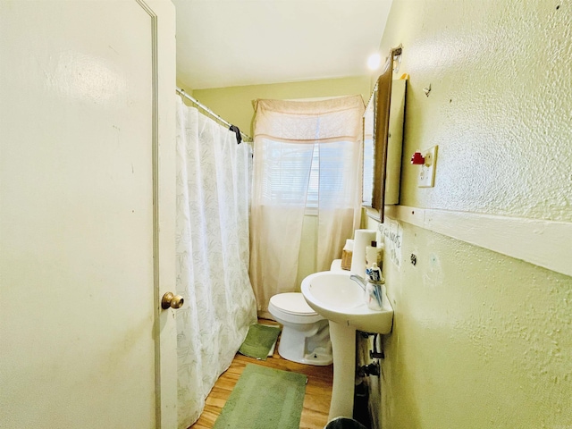 full bath with curtained shower, toilet, wood finished floors, and a textured wall