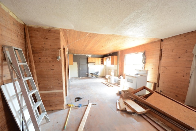 empty room with washer / dryer, a textured ceiling, and wood walls