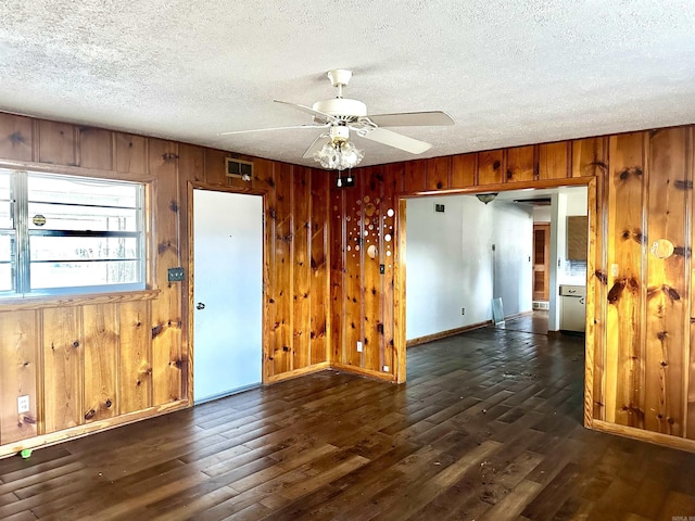 unfurnished room featuring wooden walls, a textured ceiling, and dark wood-style flooring