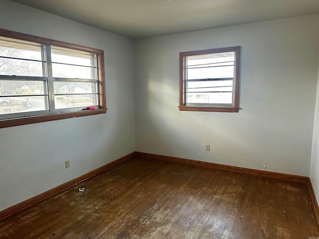 unfurnished room with plenty of natural light, baseboards, and wood-type flooring