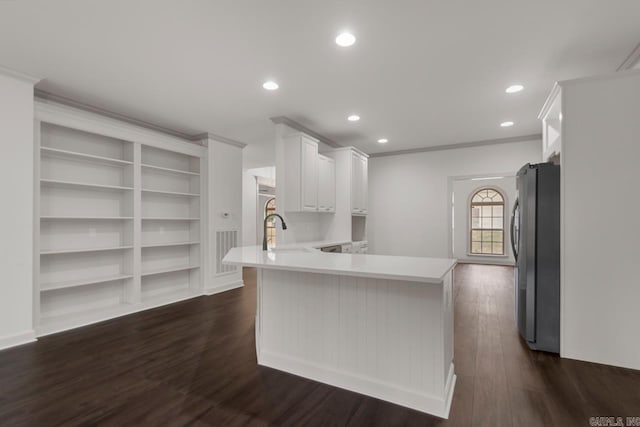 kitchen featuring dark wood-type flooring, light countertops, ornamental molding, a peninsula, and freestanding refrigerator