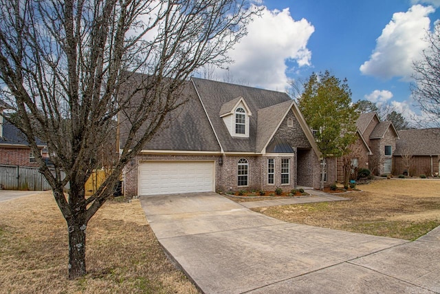 view of front facade with a front yard, fence, driveway, a garage, and brick siding