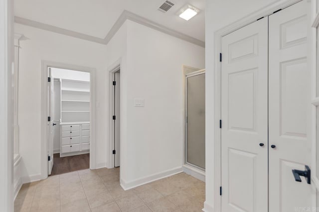 hallway with crown molding, light tile patterned floors, baseboards, and visible vents