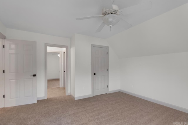 unfurnished bedroom featuring baseboards, carpet, a ceiling fan, and vaulted ceiling