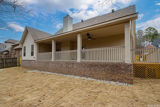 back of house featuring ceiling fan, a chimney, and a shingled roof