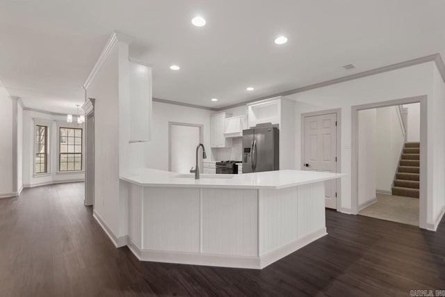 kitchen featuring stainless steel fridge, a peninsula, crown molding, and a sink