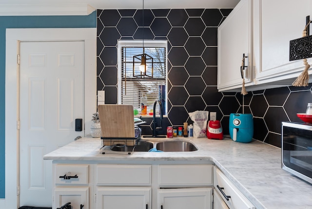 kitchen with light countertops, white cabinets, backsplash, and a sink