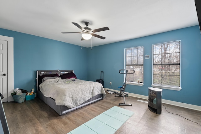 bedroom with wood finished floors, a ceiling fan, and baseboards