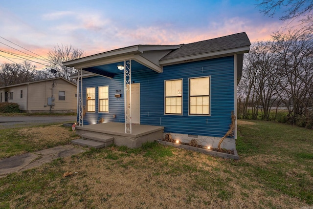 view of front of property with crawl space, a shingled roof, and a yard