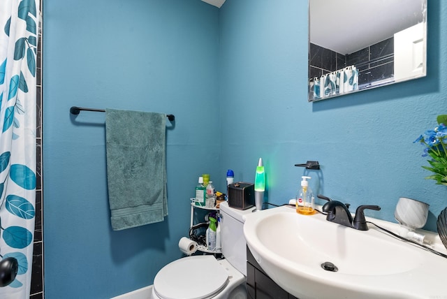 bathroom with a sink, curtained shower, and toilet