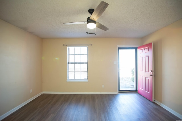 empty room with visible vents, baseboards, and dark wood finished floors