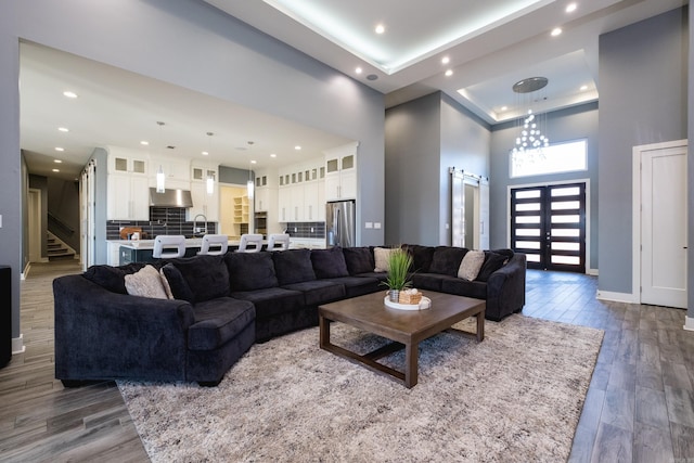 living room featuring baseboards, stairs, recessed lighting, a towering ceiling, and wood finished floors