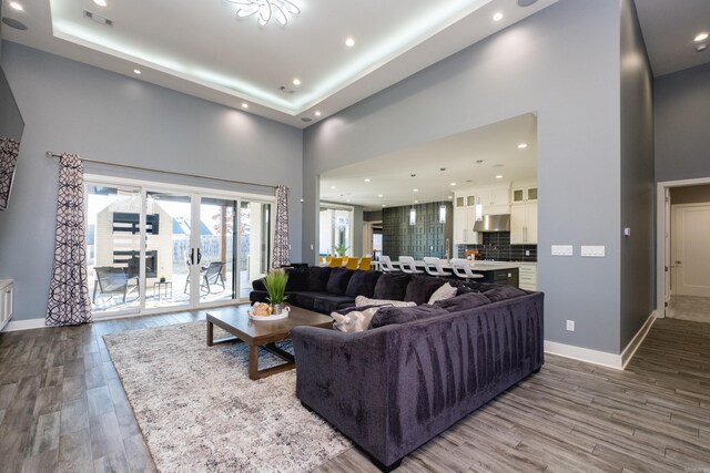 living room featuring visible vents, baseboards, a high ceiling, and wood finished floors