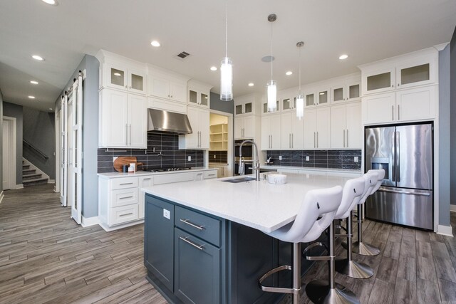 kitchen with visible vents, appliances with stainless steel finishes, ventilation hood, and light countertops