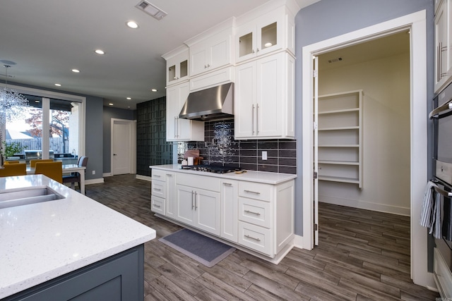 kitchen featuring white cabinets, wall chimney exhaust hood, visible vents, and backsplash