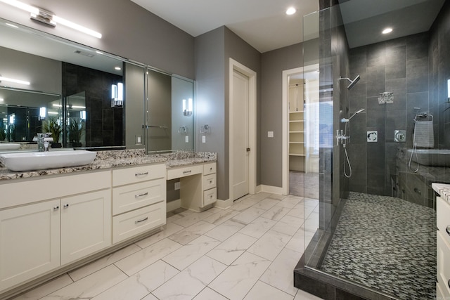 full bathroom featuring marble finish floor, a walk in shower, vanity, baseboards, and a spacious closet