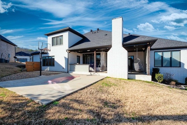 back of property with roof with shingles, a yard, a chimney, a patio area, and brick siding