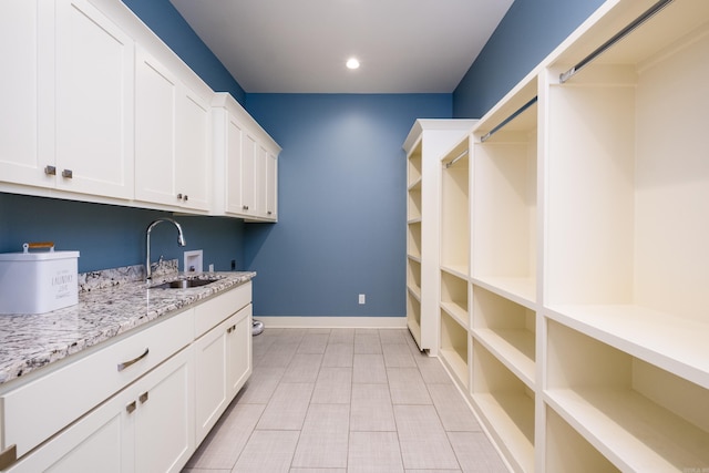 washroom featuring baseboards, washer hookup, recessed lighting, cabinet space, and a sink