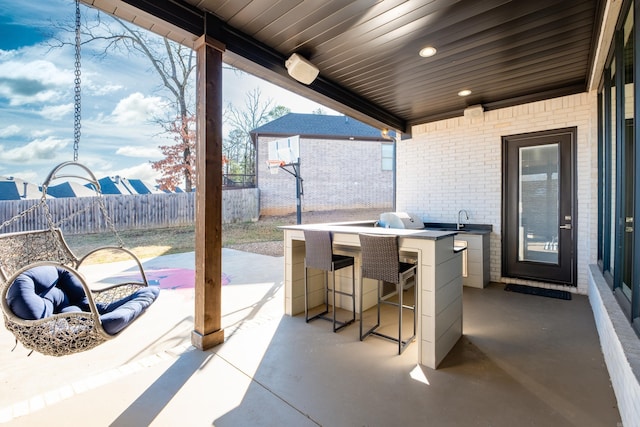 view of patio with outdoor wet bar, exterior kitchen, fence, and a sink