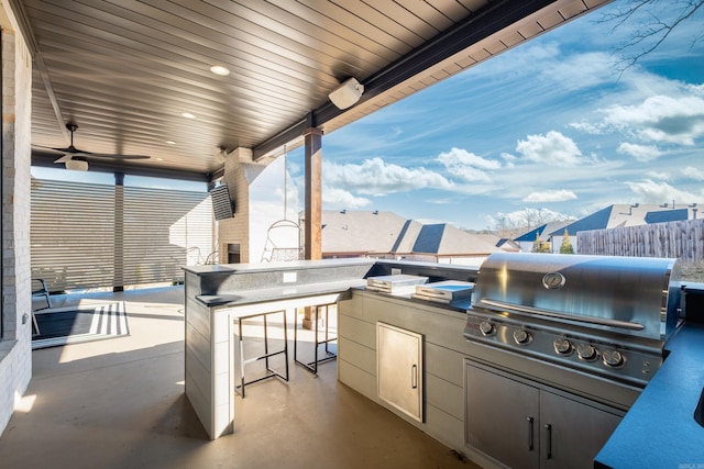 view of patio / terrace featuring fence, an outdoor kitchen, outdoor wet bar, ceiling fan, and grilling area