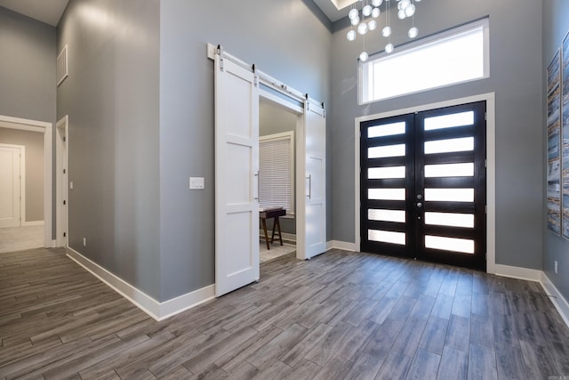 foyer featuring a barn door, a high ceiling, and wood finished floors