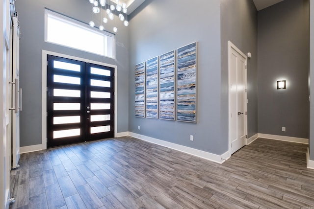 foyer entrance featuring a high ceiling, baseboards, and wood finished floors