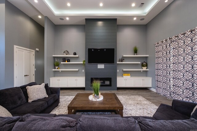 living room featuring visible vents, a fireplace, a raised ceiling, and dark wood-type flooring