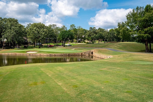 view of home's community featuring view of golf course, a lawn, and a water view