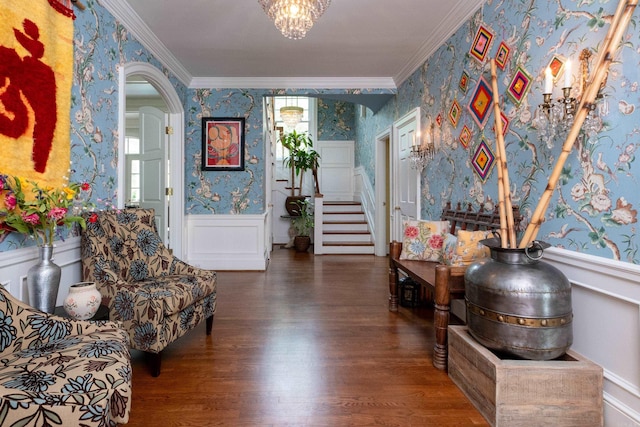 sitting room with wallpapered walls, ornamental molding, wood finished floors, and wainscoting