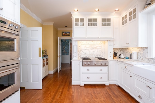 kitchen with stainless steel appliances, backsplash, ornamental molding, and white cabinetry