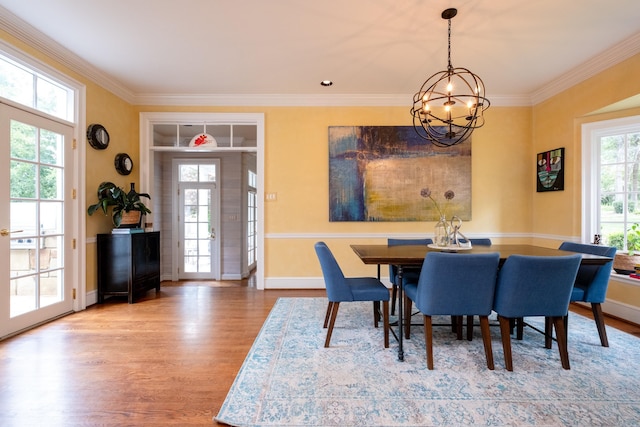 dining area featuring crown molding, an inviting chandelier, and wood finished floors