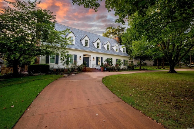 new england style home with concrete driveway and a front lawn