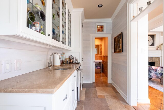 bar with a tiled fireplace, crown molding, and a sink