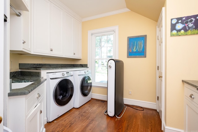 washroom featuring wood finished floors, baseboards, washing machine and clothes dryer, cabinet space, and ornamental molding