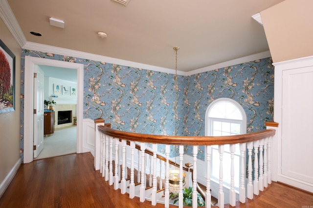 hall featuring wallpapered walls, an upstairs landing, wood finished floors, and ornamental molding