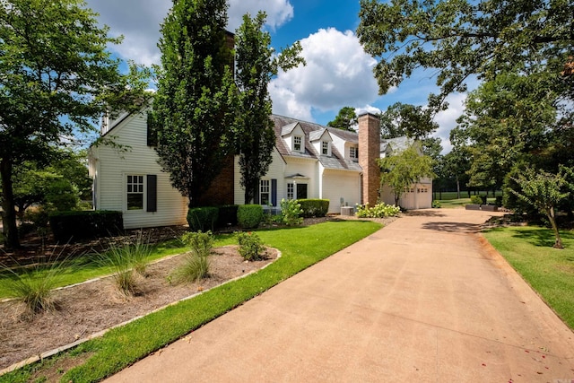 cape cod house with a front yard, driveway, and a chimney