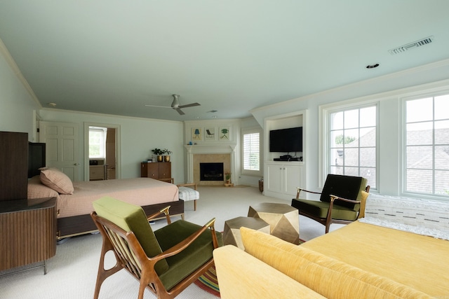 bedroom featuring visible vents, a fireplace, crown molding, light colored carpet, and ceiling fan