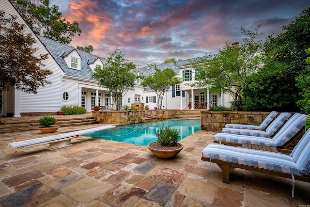 outdoor pool with french doors, a patio, and a diving board