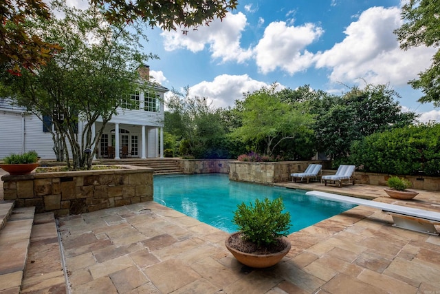 pool featuring a patio, an exterior structure, a diving board, an outdoor structure, and french doors