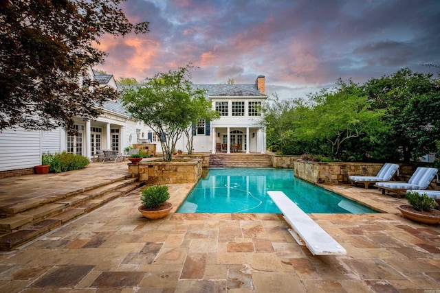 view of swimming pool with a diving board, french doors, a fenced in pool, and a patio area