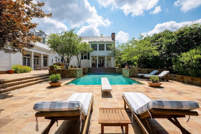 view of pool featuring a patio area, a fenced in pool, french doors, and a diving board