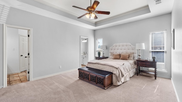 carpeted bedroom featuring visible vents, a raised ceiling, ensuite bath, and crown molding