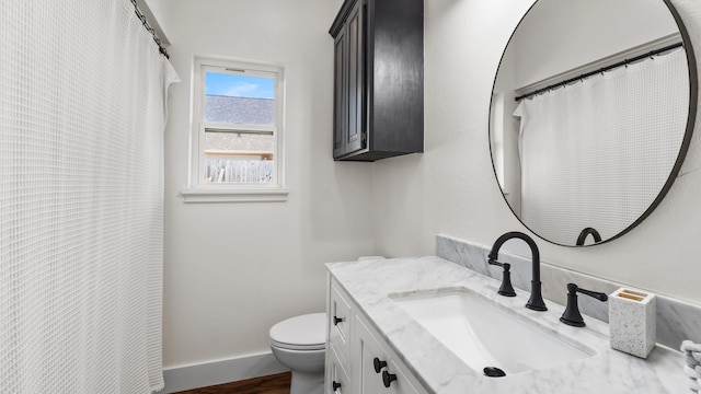 bathroom featuring baseboards, toilet, wood finished floors, and vanity